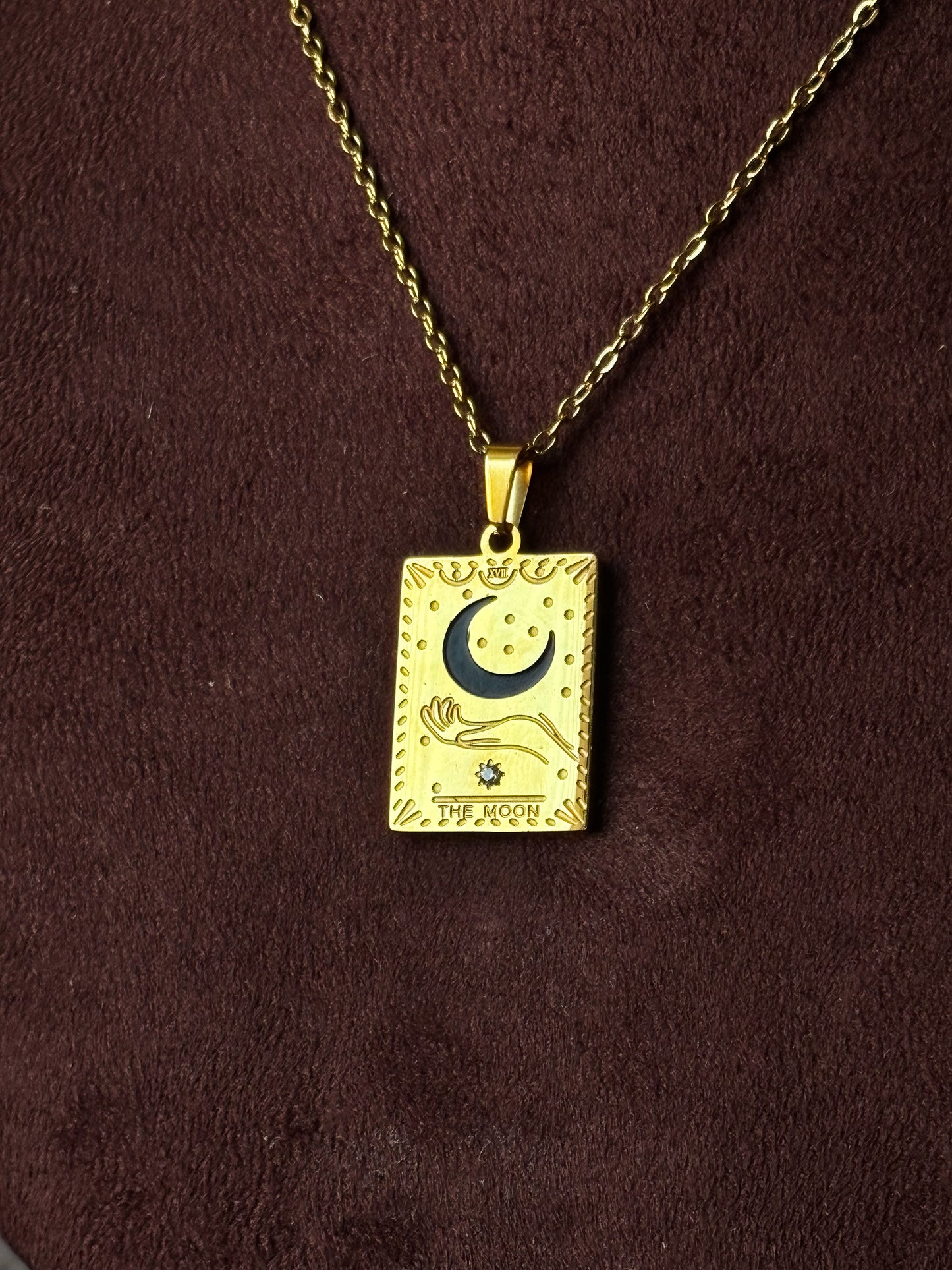 Gold necklace with a rectangular pendant featuring a moon and star design.