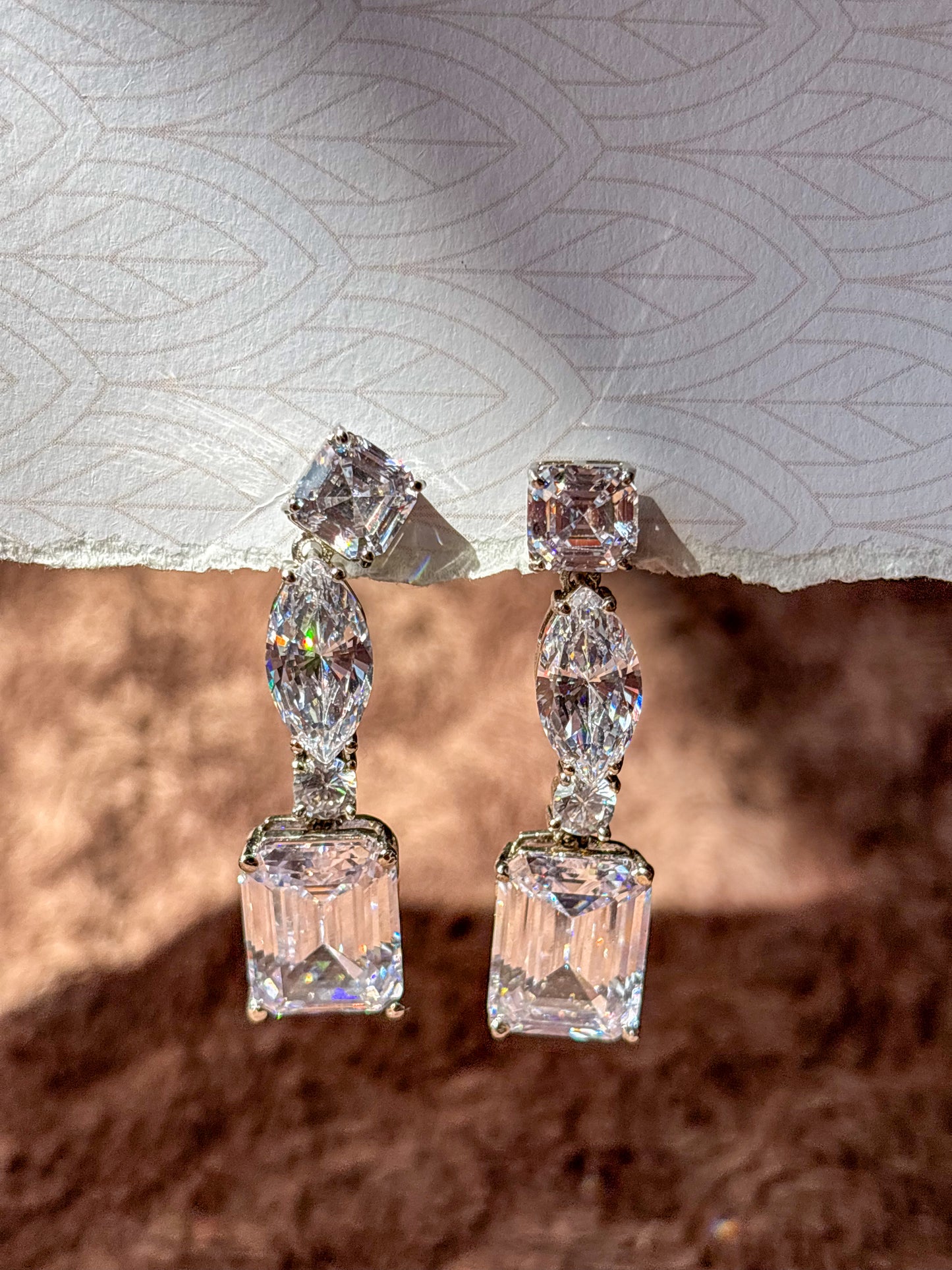 Elegant AD drop earrings with emerald-cut and marquise-shaped stones. Sparkling silver-tone statement earrings perfect for weddings, festive wear and party looks.