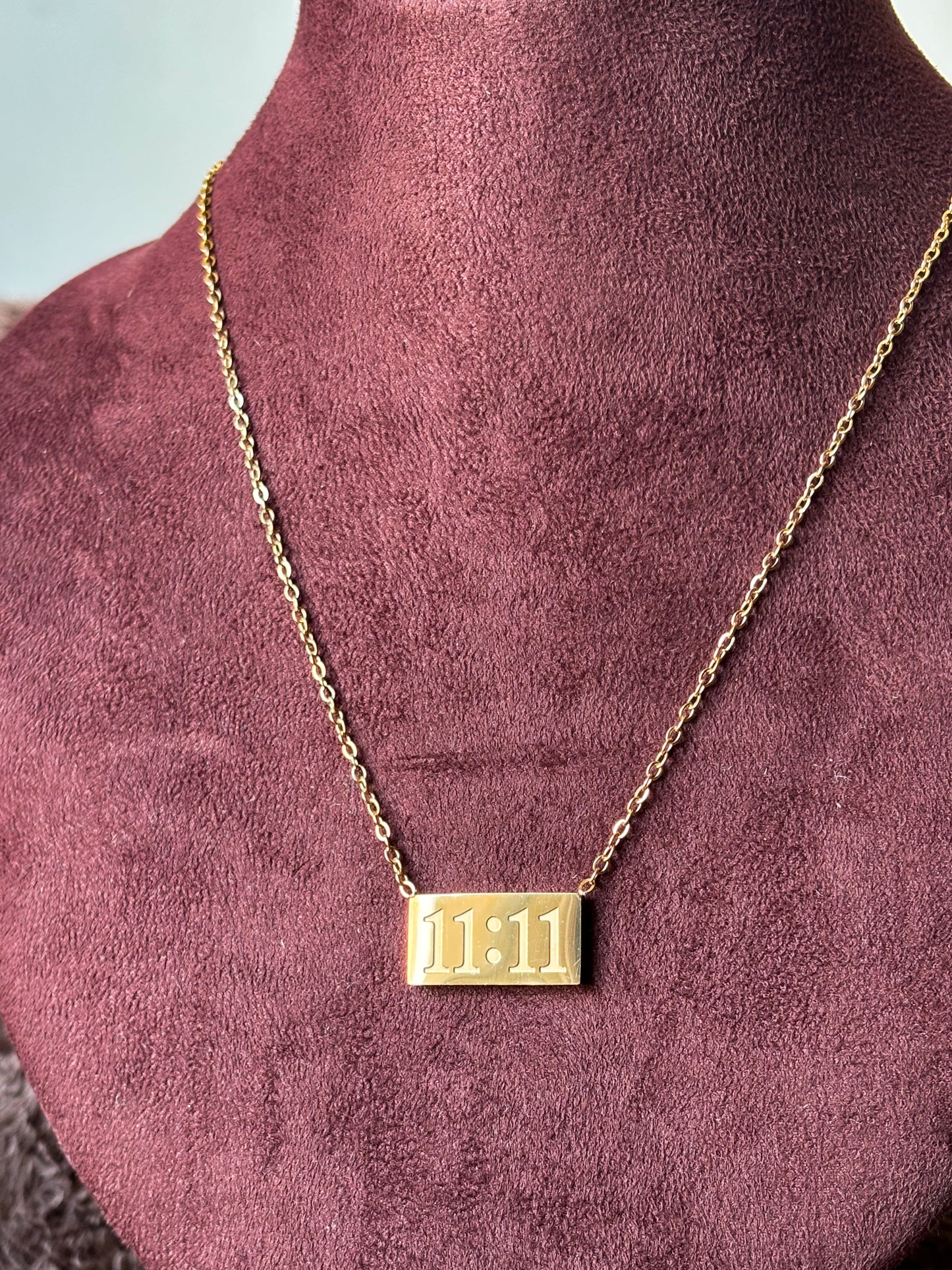 Gold 11:11 manifestation necklace with a rectangular engraved pendant on a delicate gold chain. Minimalist everyday jewelry symbolizing positivity, wishes and new beginnings.