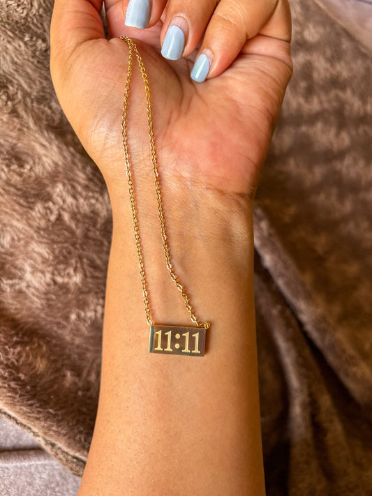 Gold 11:11 manifestation necklace with a rectangular engraved pendant on a delicate gold chain. Minimalist everyday jewelry symbolizing positivity, wishes and new beginnings.