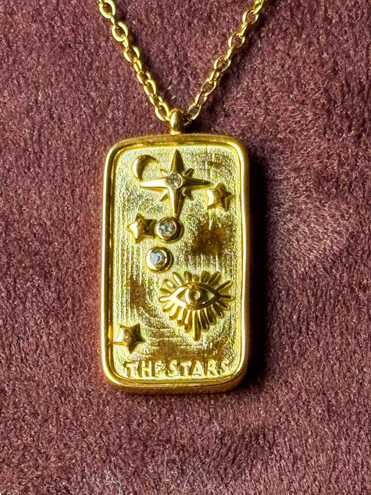 Elegant gold celestial tarot pendant necklace with sun, moon, and star detailing on a delicate chain, styled on a model’s neck for a minimal luxury look.