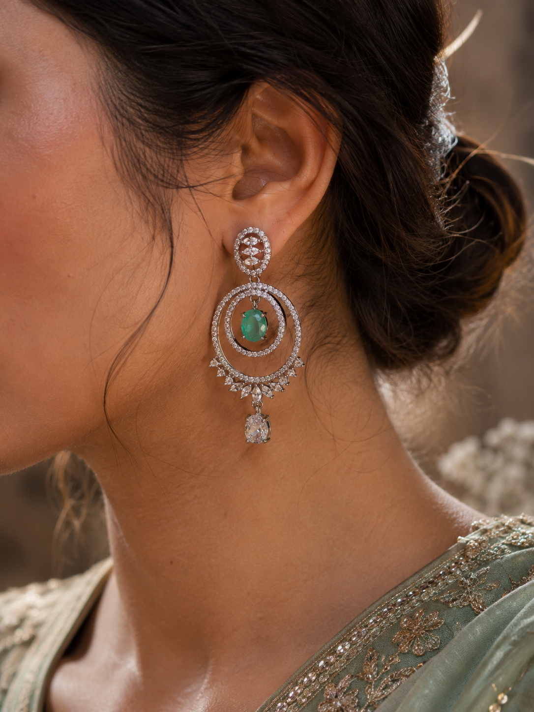 Elegant silver-tone chandelier earrings with emerald green center stones and sparkling zircon detailing.