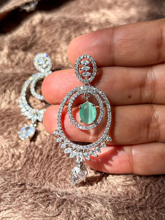 Elegant silver-tone chandelier earrings with emerald green center stones and sparkling zircon detailing.