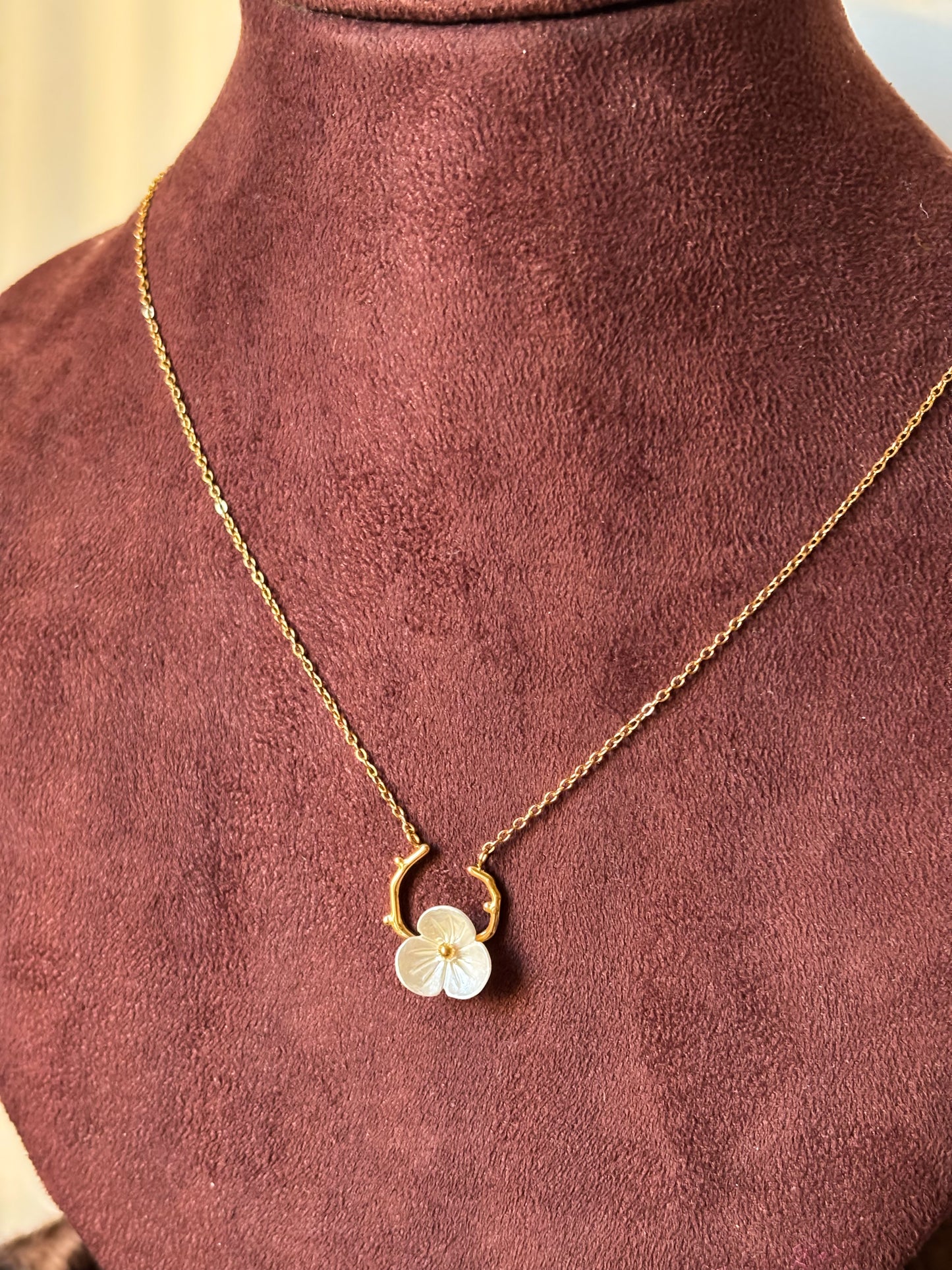 Gold necklace with a white Floral pendant on a golden branch