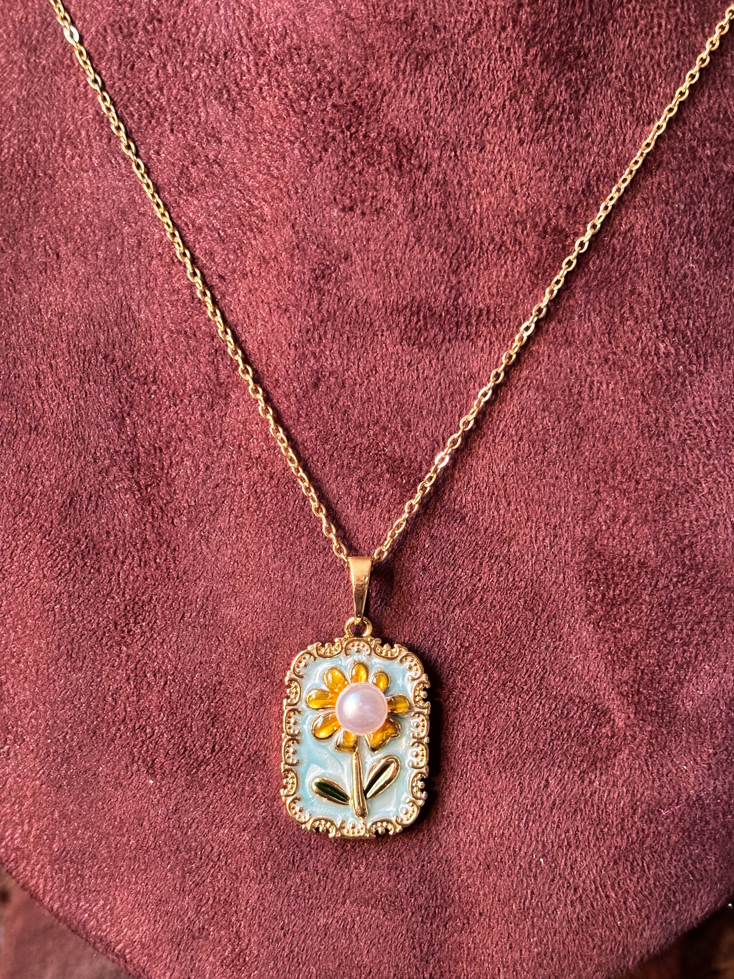Gold Sunflower pendant necklace with blue enamel and pink pearl center on a gold chain