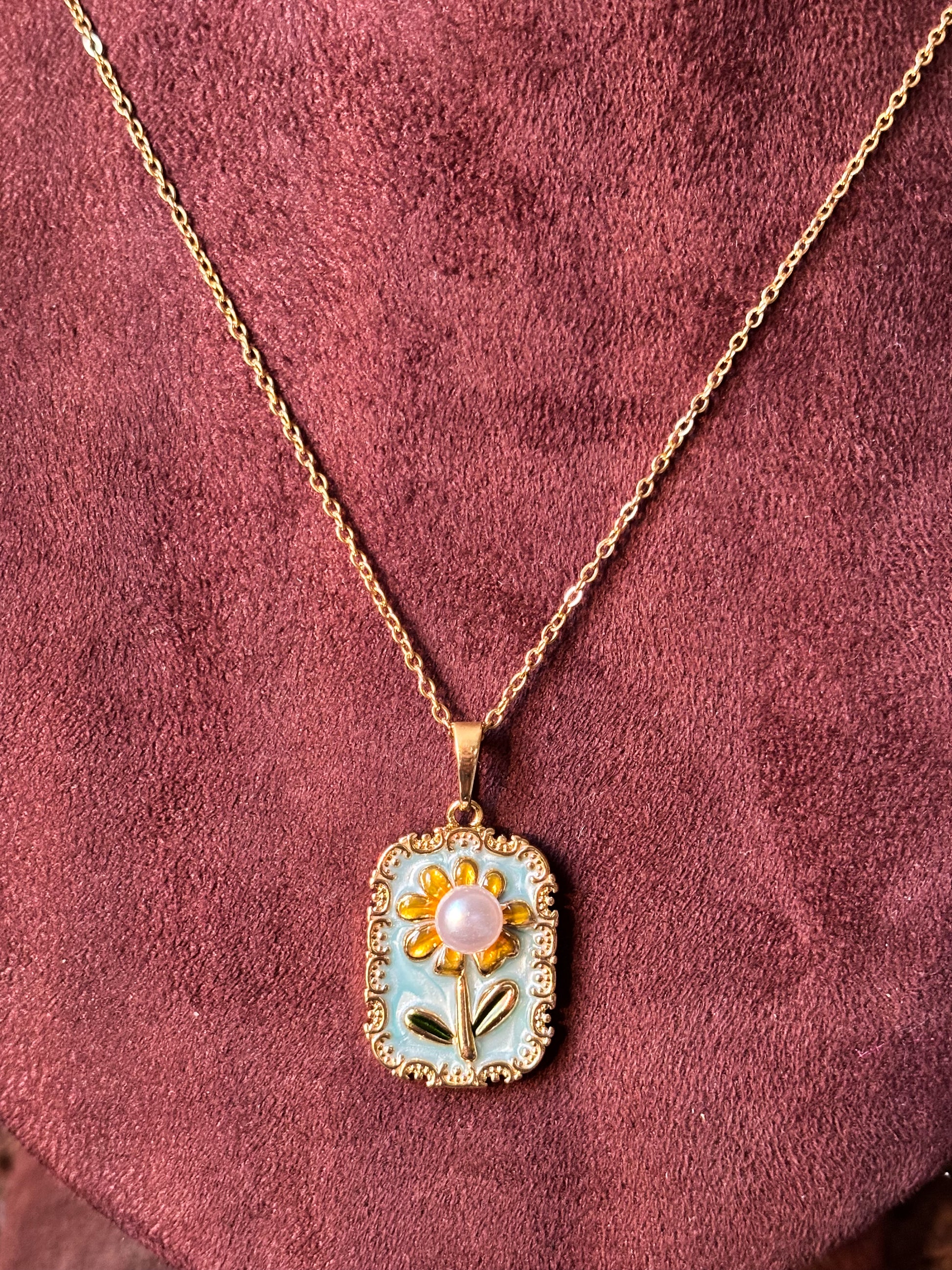 Gold Sunflower pendant necklace with blue enamel and pink pearl center on a gold chain