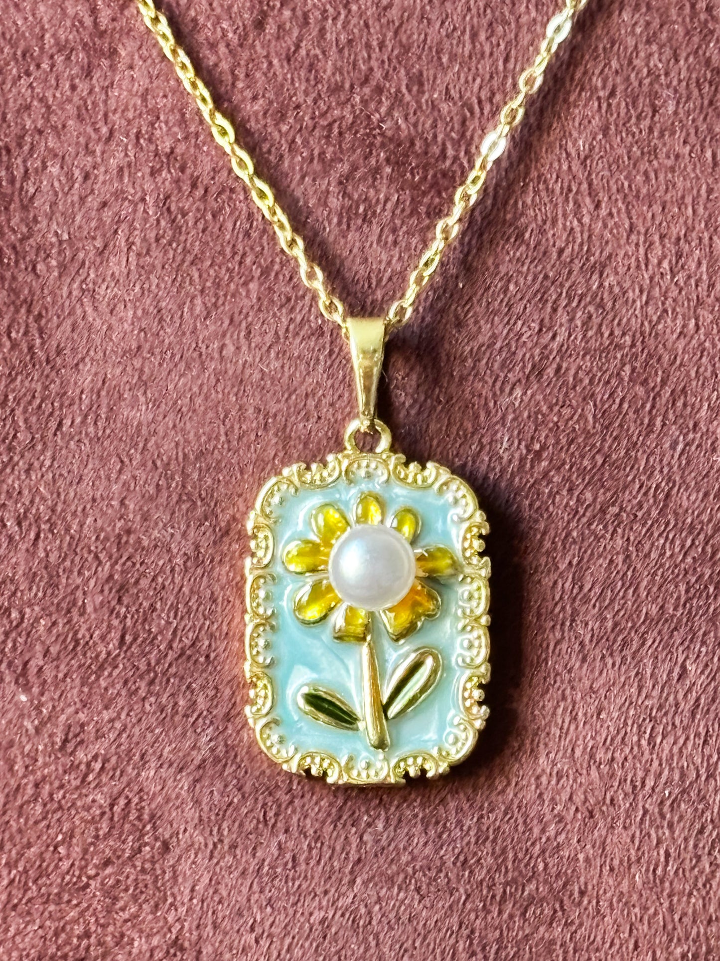 Necklace with a pendant featuring a sunflower design on a baby blue background with pearl
