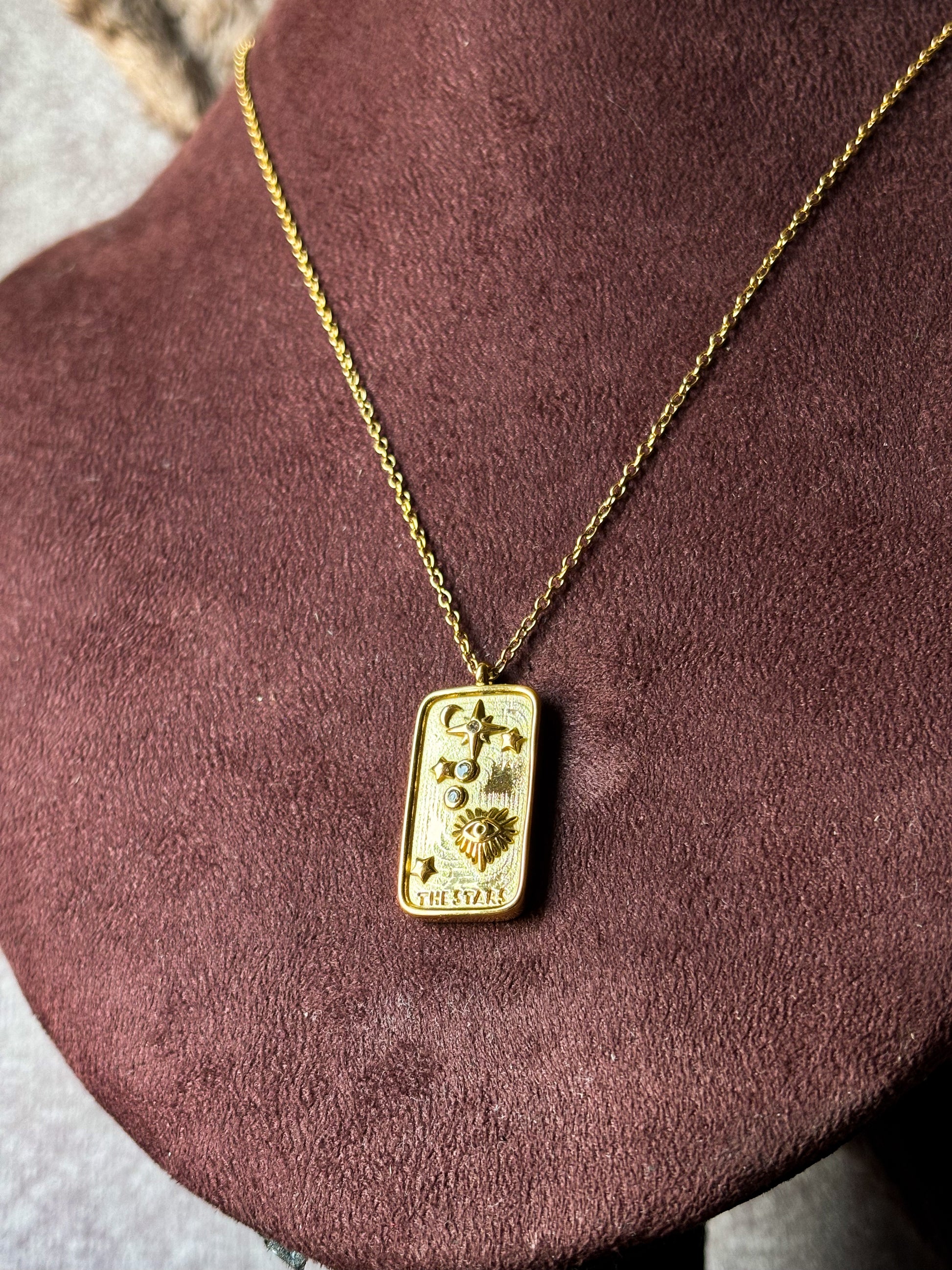 Elegant gold celestial tarot pendant necklace with sun, moon, and star detailing on a delicate chain, styled on a model’s neck for a minimal luxury look.