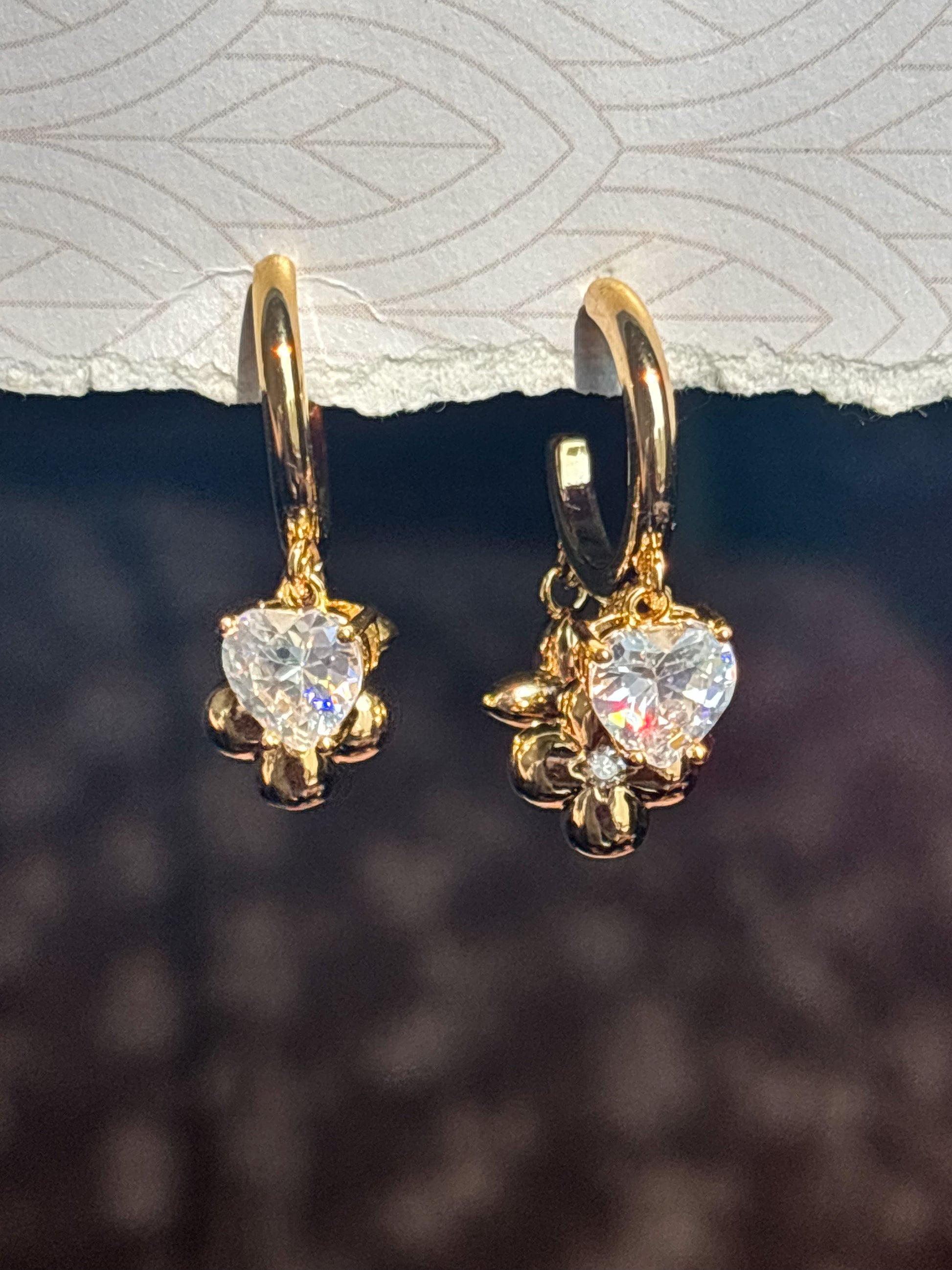 Gold hoop earrings with heart-shaped crystal and floral charm detail