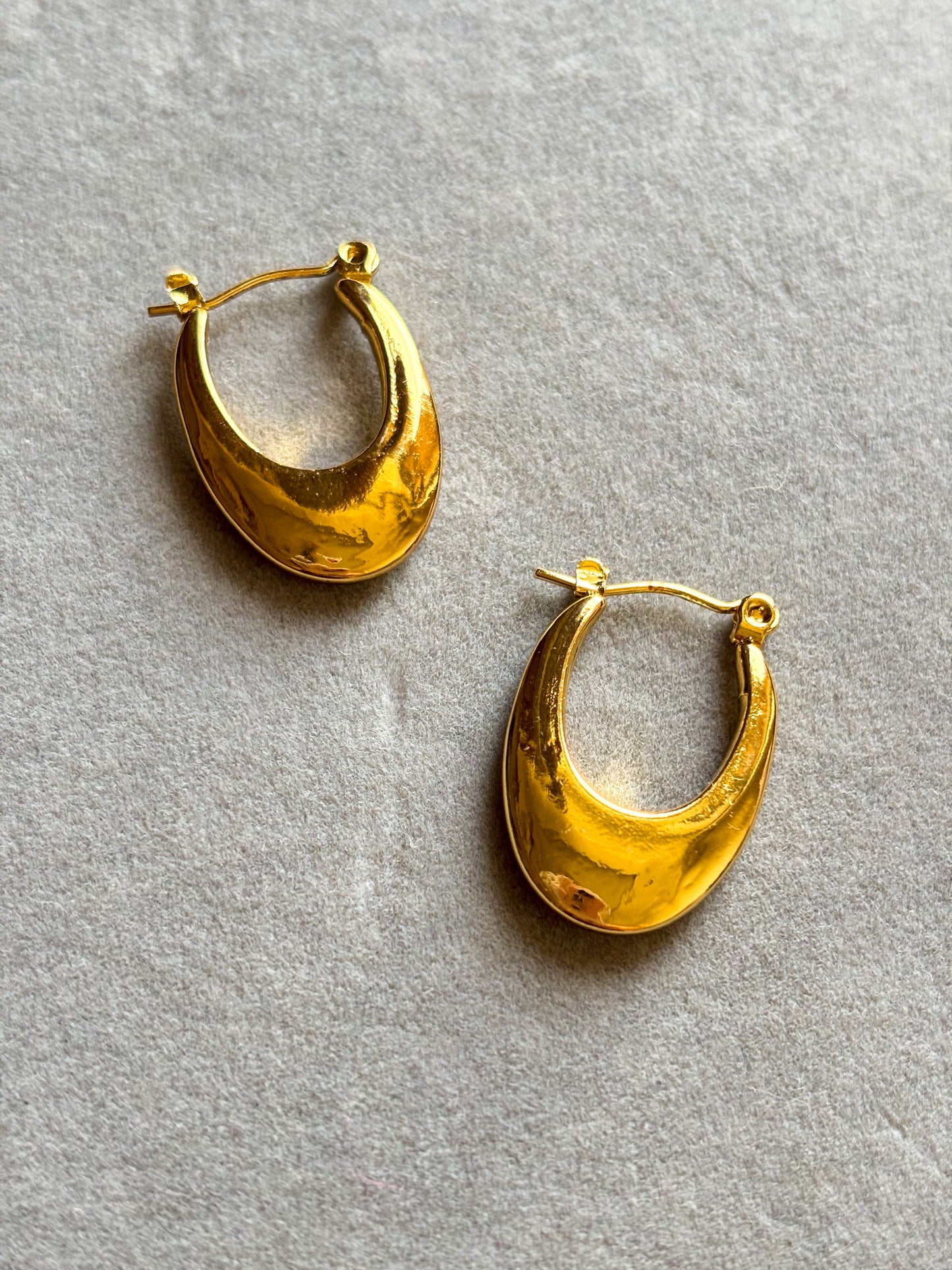 Elegant anti-tarnish gold teardrop hoop earrings with a sleek polished finish, on an aesthetic background. Lightweight, waterproof statement hoops perfect for everyday wear and special occasions.