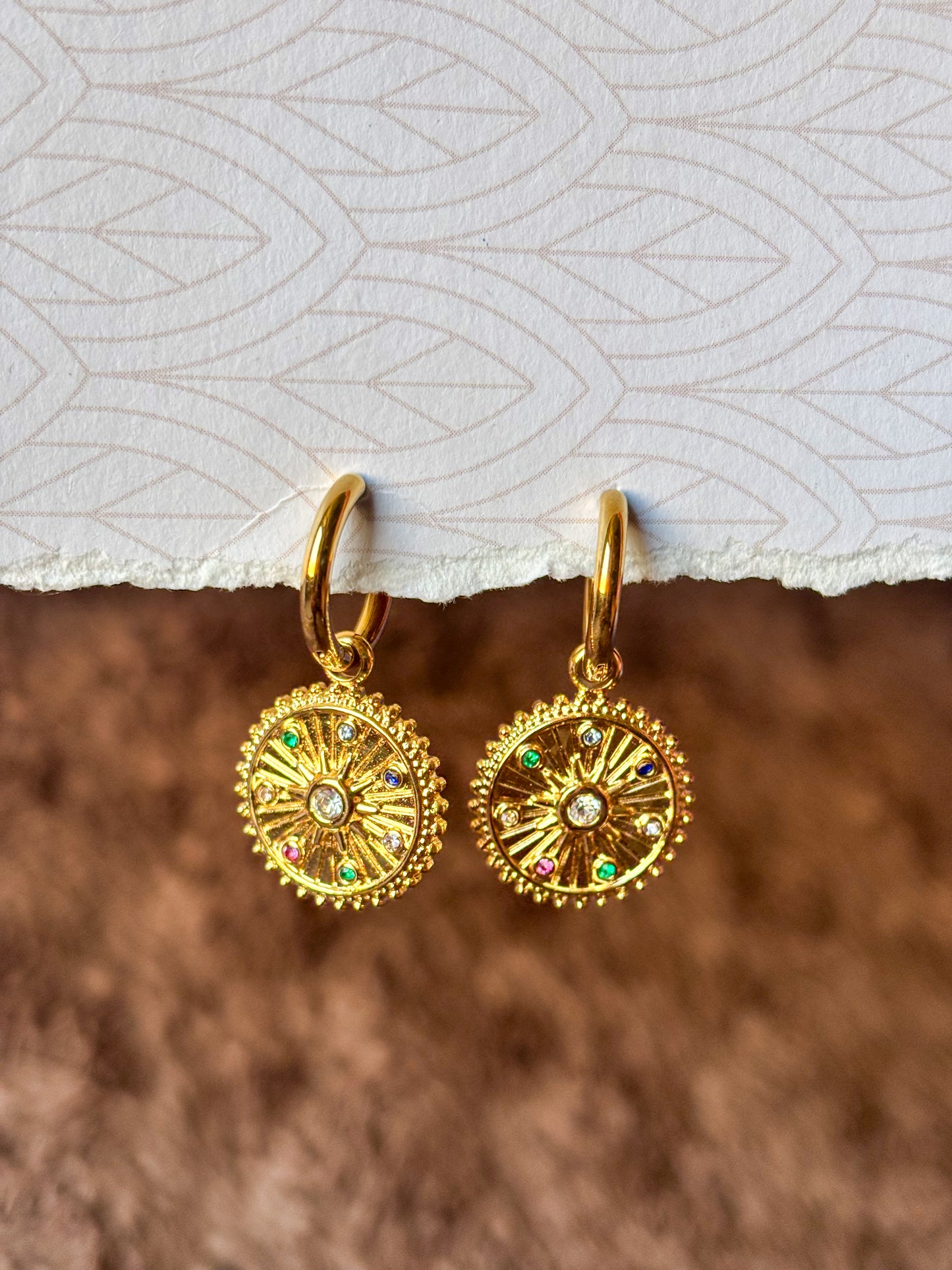 Elegant gold hoop earrings featuring celestial-inspired pendants and multicolor stones.
