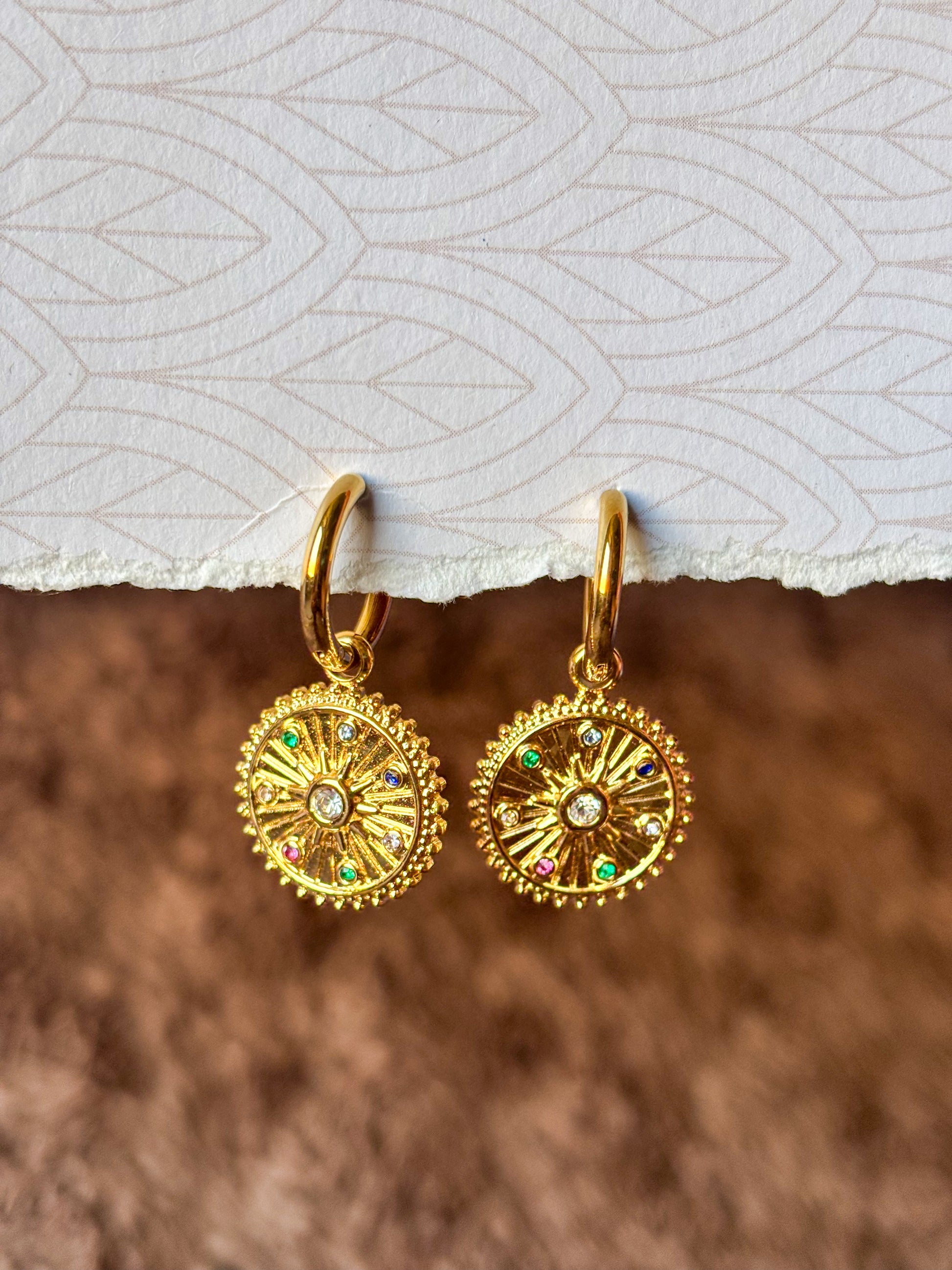 Elegant gold hoop earrings featuring celestial-inspired pendants and multicolor stones.