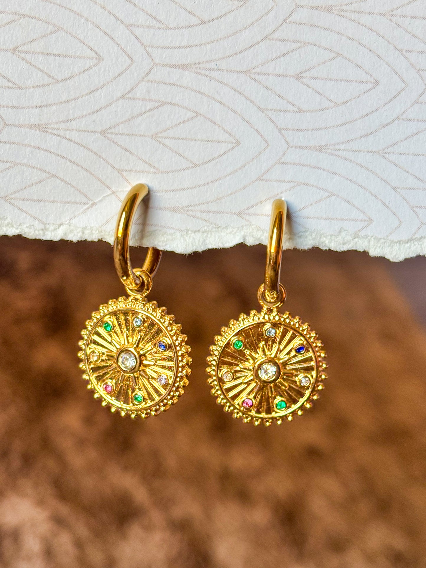 Elegant gold hoop earrings featuring celestial-inspired pendants and multicolor stones.
