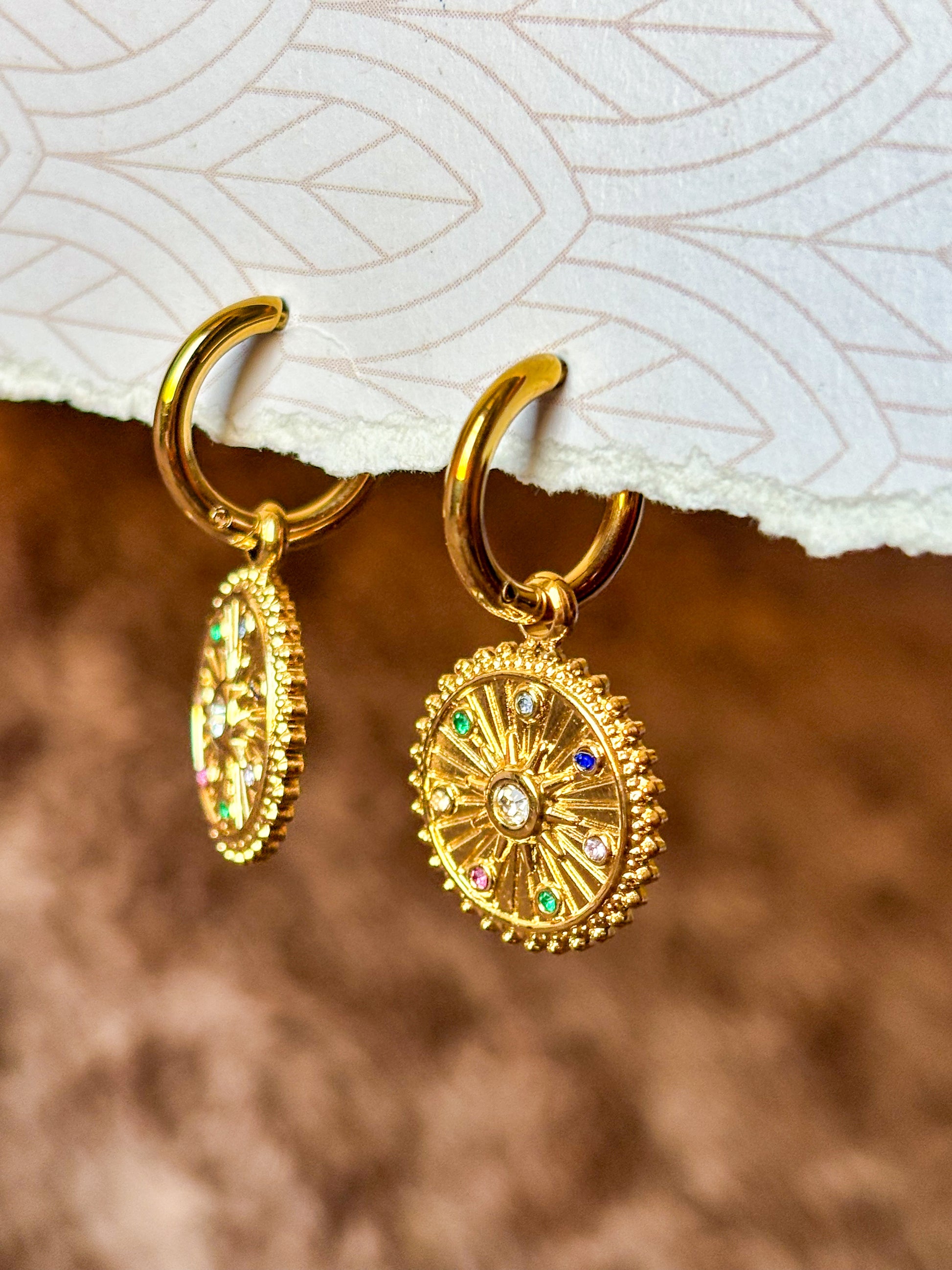 Elegant gold hoop earrings featuring celestial-inspired pendants and multicolor stones.