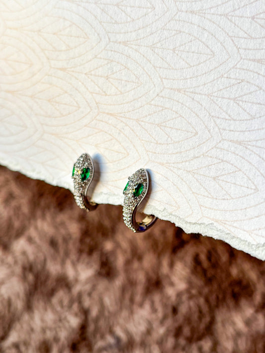 A sparkling emerald serpent hoop earring featuring pavé-set crystals and vibrant green gemstone eyes.