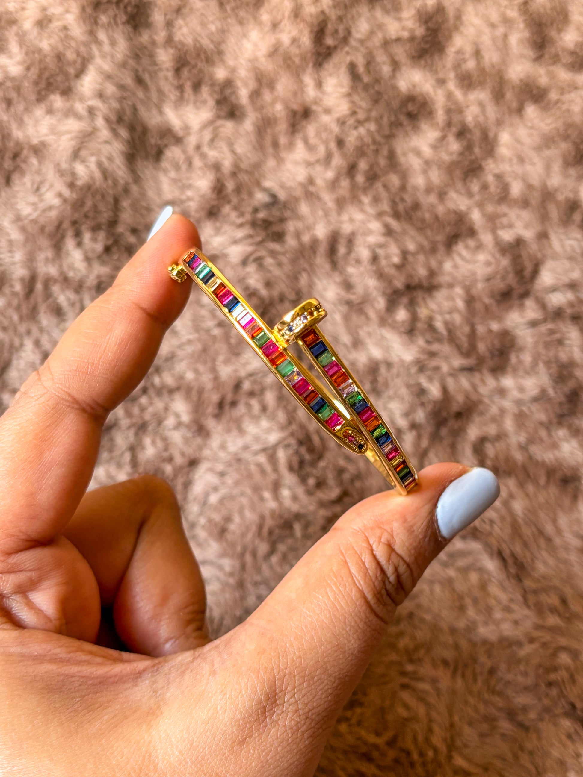 Gold-tone anti-tarnish nail bracelet featuring vibrant multicolor baguette-cut stones in a sleek open cuff design. A trendy statement bracelet perfect for everyday wear, stacking and gifting.