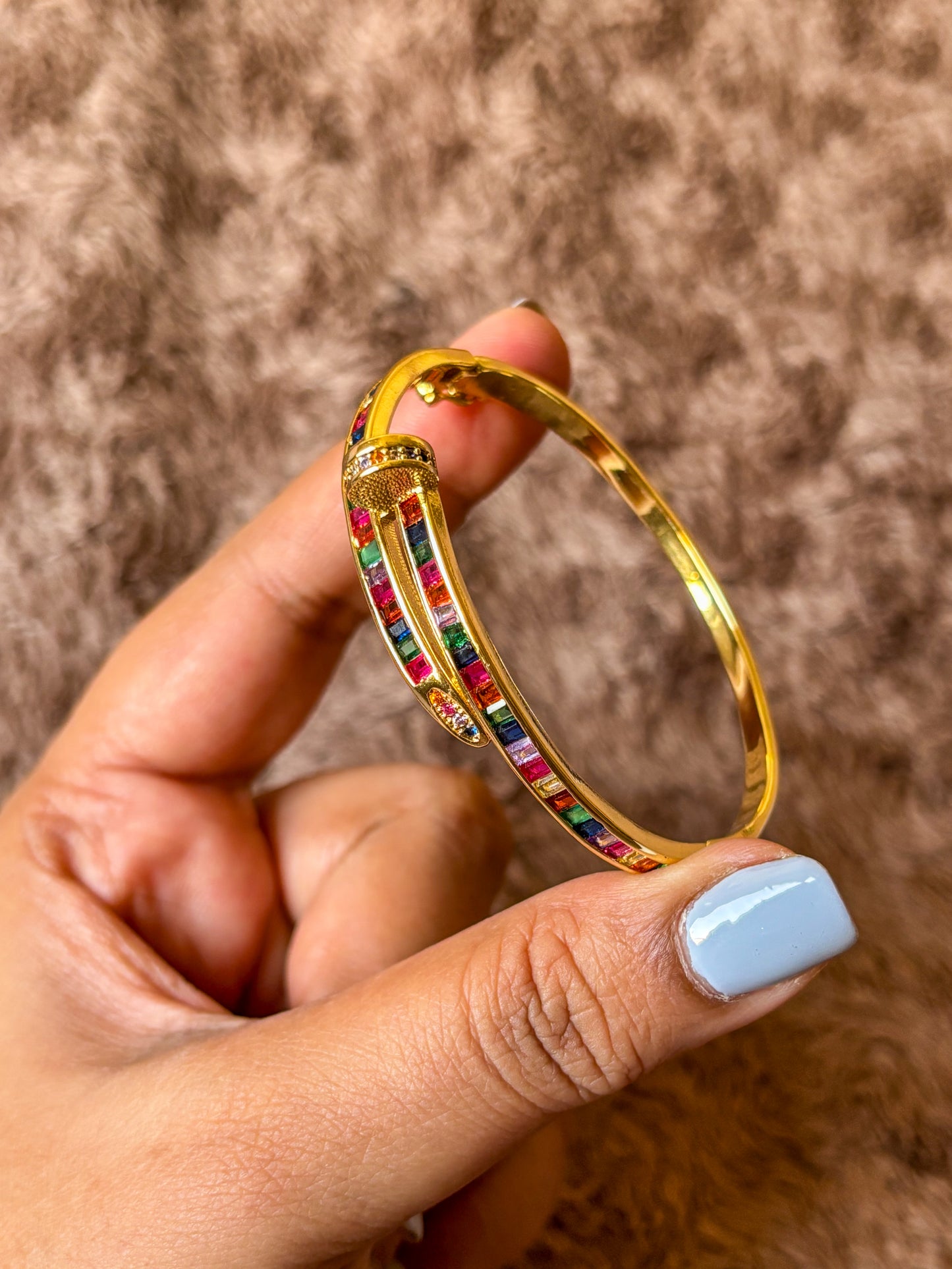 Gold-tone anti-tarnish nail bracelet featuring vibrant multicolor baguette-cut stones in a sleek open cuff design. A trendy statement bracelet perfect for everyday wear, stacking and gifting.