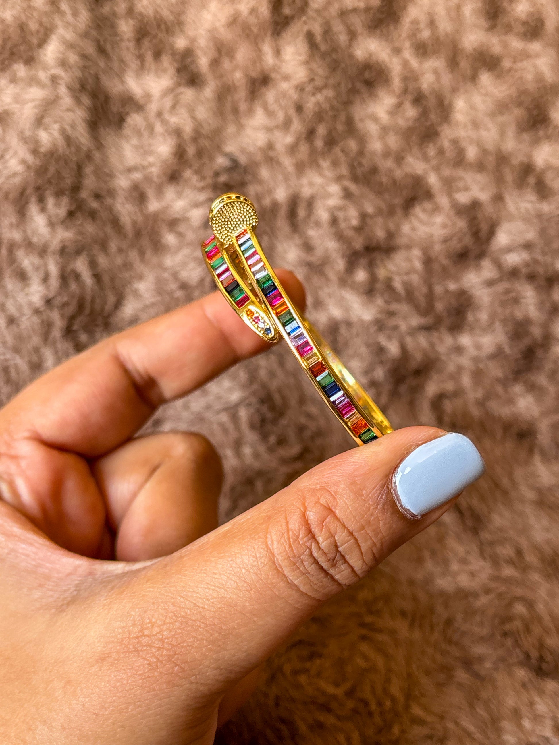 Gold-tone anti-tarnish nail bracelet featuring vibrant multicolor baguette-cut stones in a sleek open cuff design. A trendy statement bracelet perfect for everyday wear, stacking and gifting.
