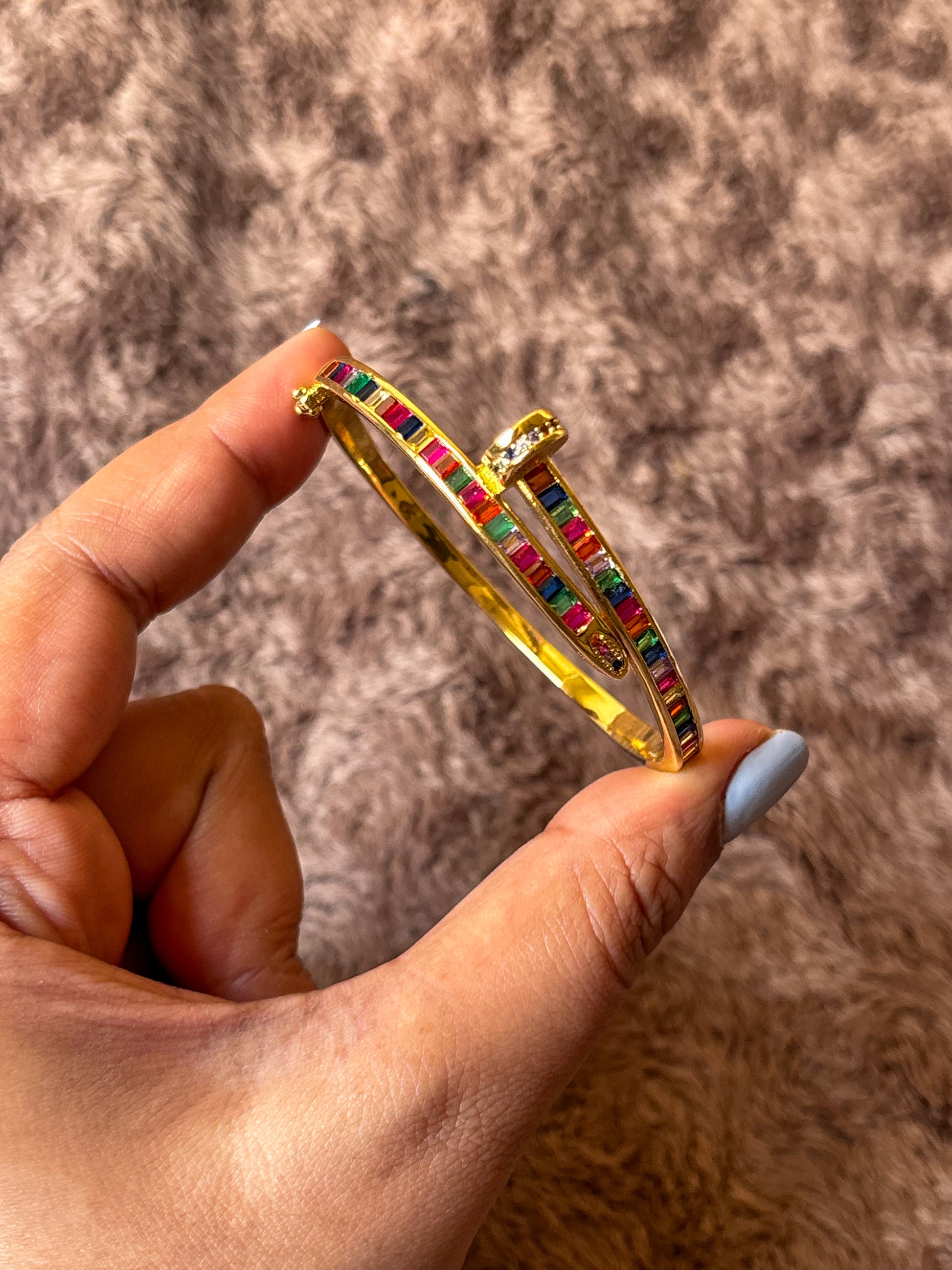 Gold-tone anti-tarnish nail bracelet featuring vibrant multicolor baguette-cut stones in a sleek open cuff design. A trendy statement bracelet perfect for everyday wear, stacking and gifting.