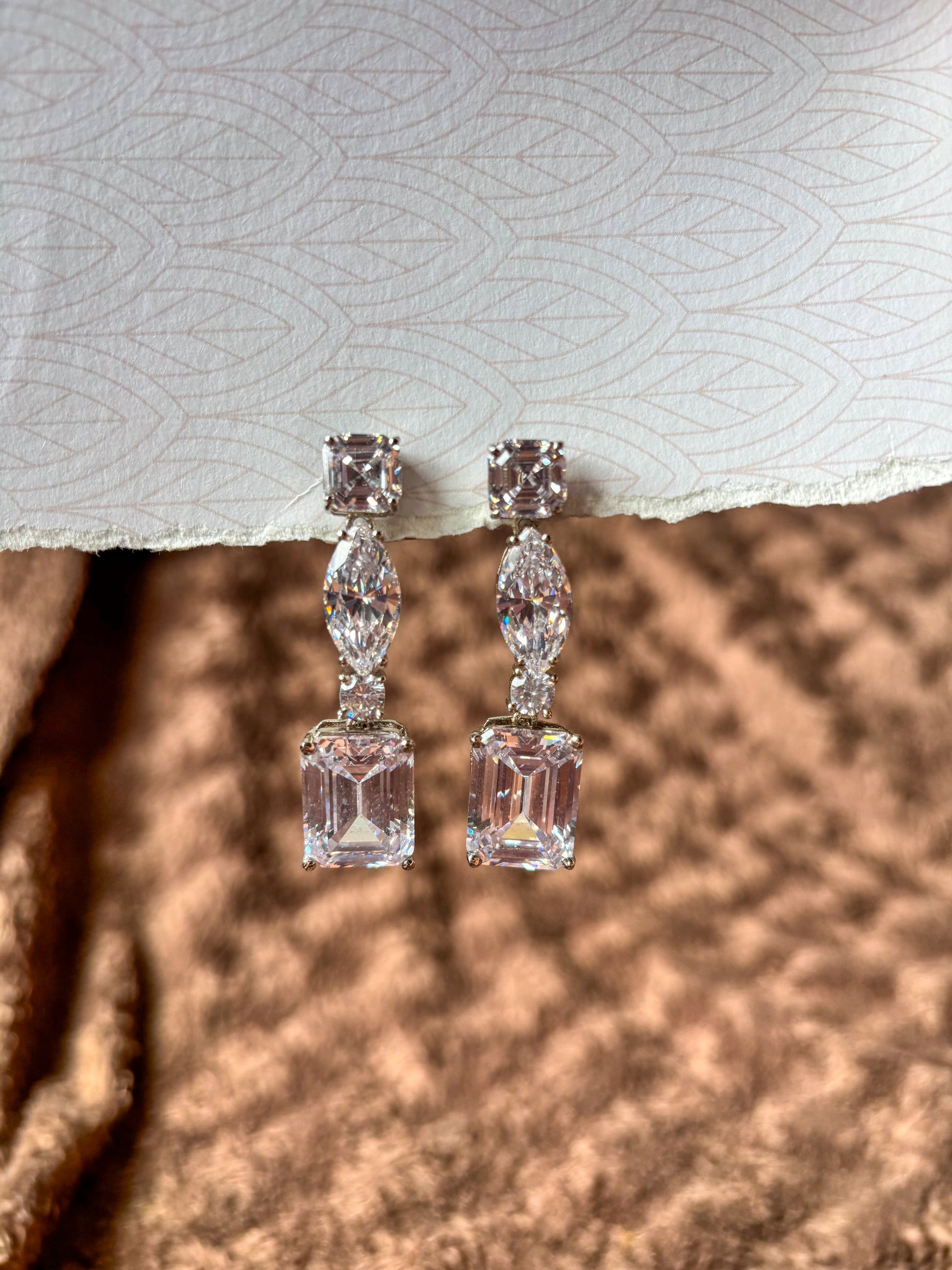 Elegant AD drop earrings with emerald-cut and marquise-shaped stones. Sparkling silver-tone statement earrings perfect for weddings, festive wear and party looks.