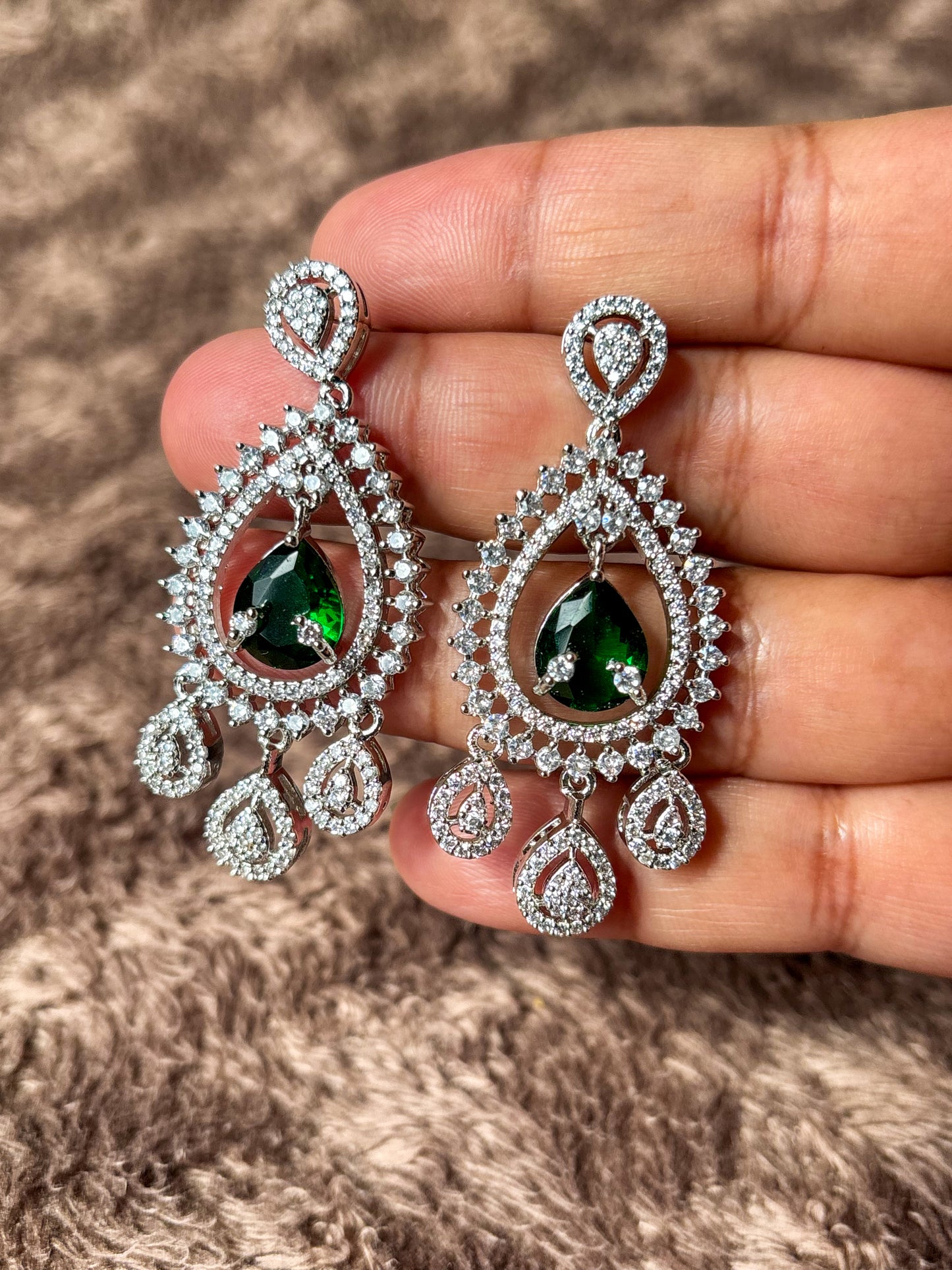 Sparkling silver-tone American Diamond (AD) Chandbali earrings featuring a large teardrop-cut crystal centerpiece, intricate pavé stone detailing and elegant dangling accents. Perfect for bridal wear, weddings, festive occasions and party styling.