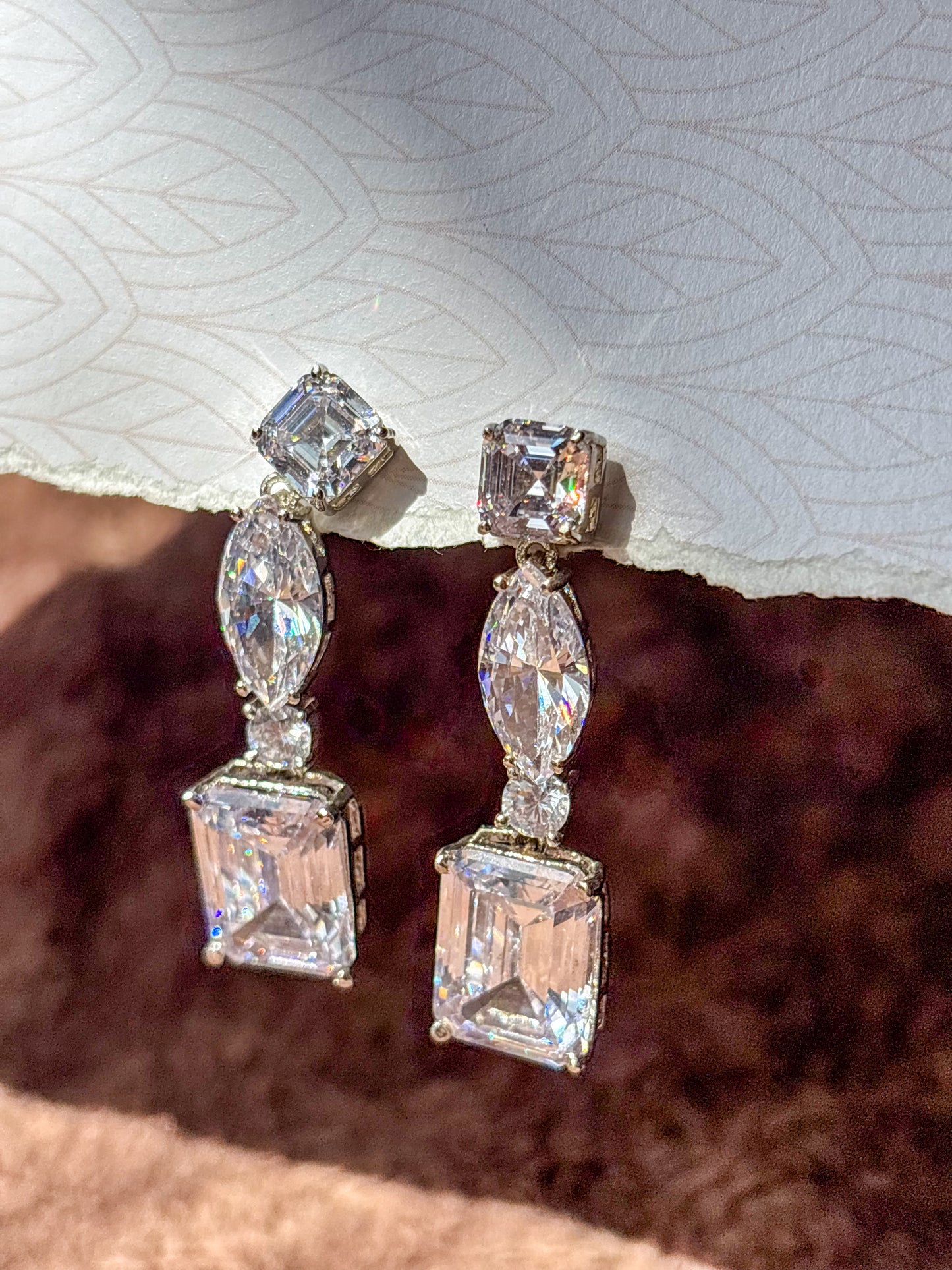 Elegant AD drop earrings with emerald-cut and marquise-shaped stones. Sparkling silver-tone statement earrings perfect for weddings, festive wear and party looks.