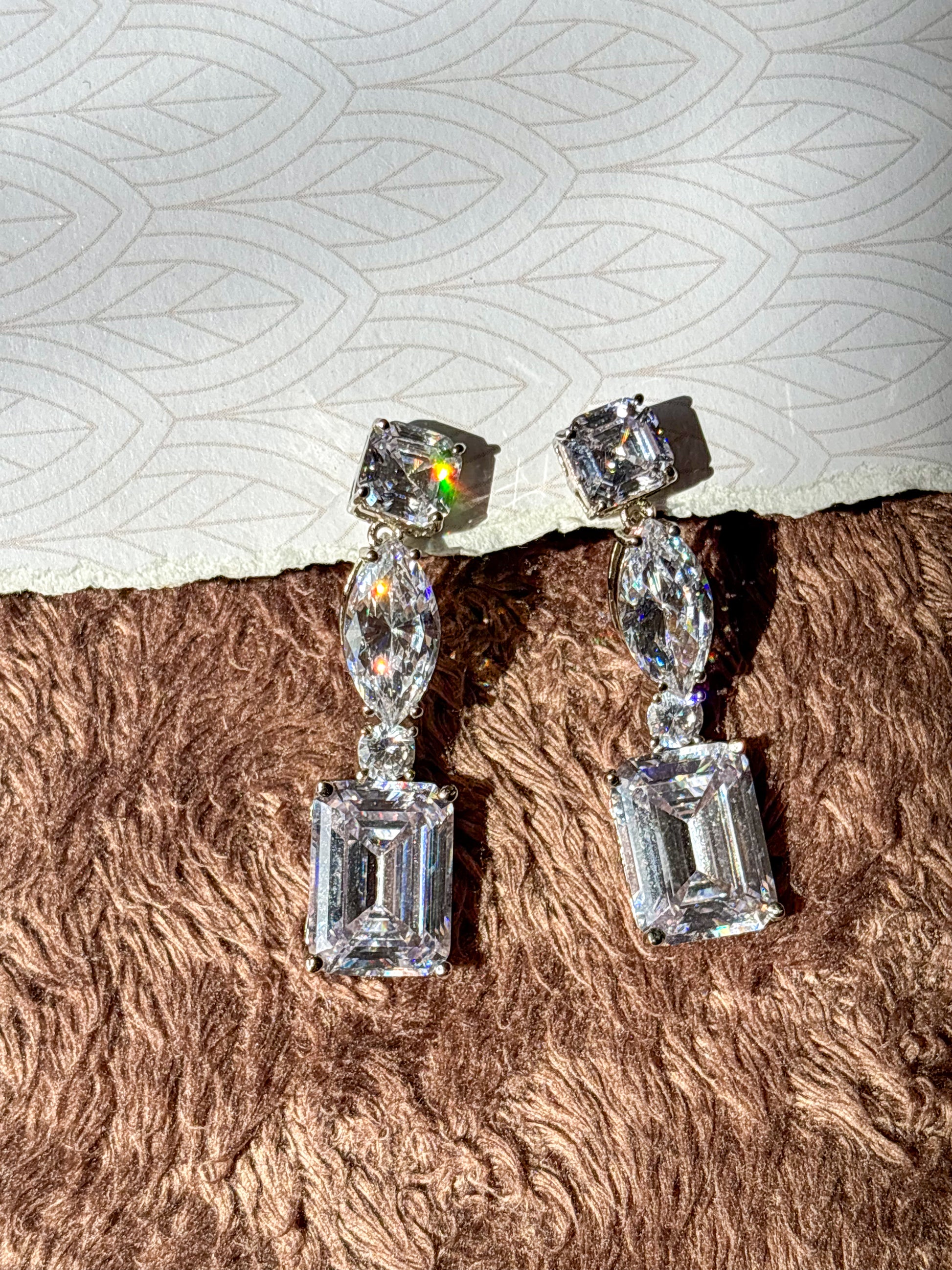 Elegant AD drop earrings with emerald-cut and marquise-shaped stones. Sparkling silver-tone statement earrings perfect for weddings, festive wear and party looks.