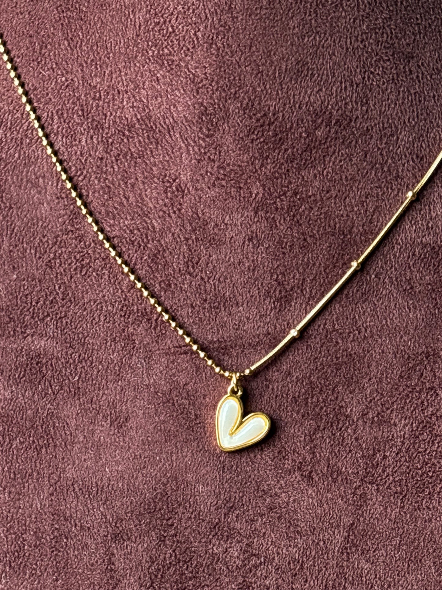 Gold-tone dual-chain necklace featuring a delicate ball chain and snake chain design with a white enamel heart pendant. Perfect minimalist jewellery for everyday wear.
