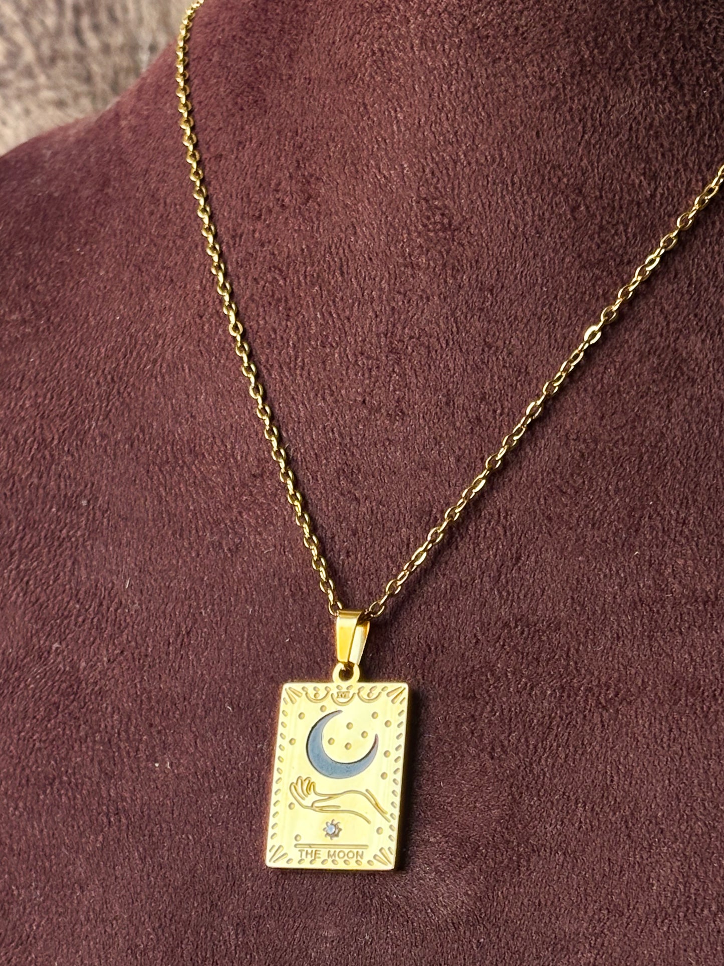 Gold necklace with a rectangular pendant featuring a moon and star design.
