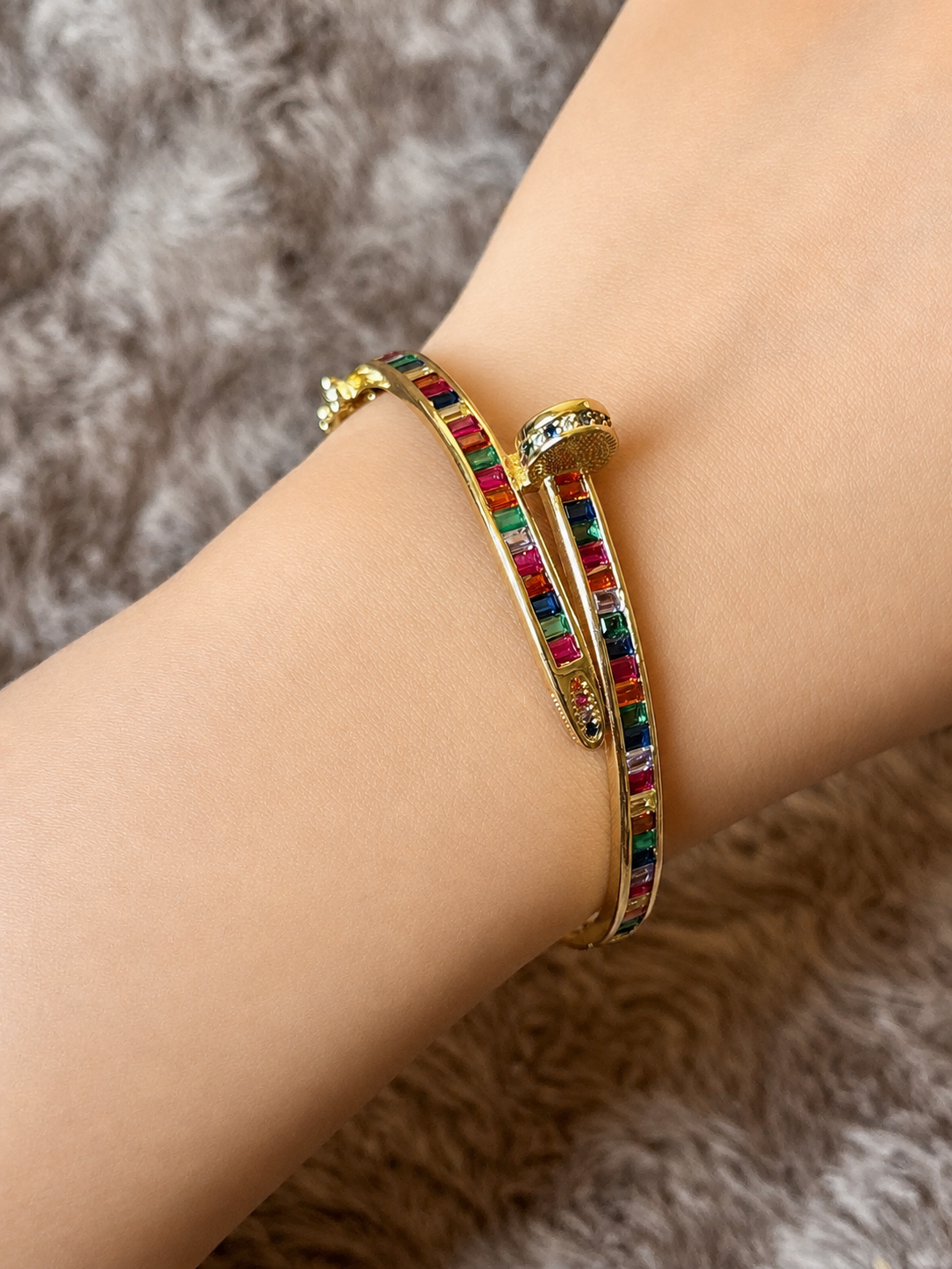 Gold-tone anti-tarnish nail bracelet featuring vibrant multicolor baguette-cut stones in a sleek open cuff design. A trendy statement bracelet perfect for everyday wear, stacking and gifting.