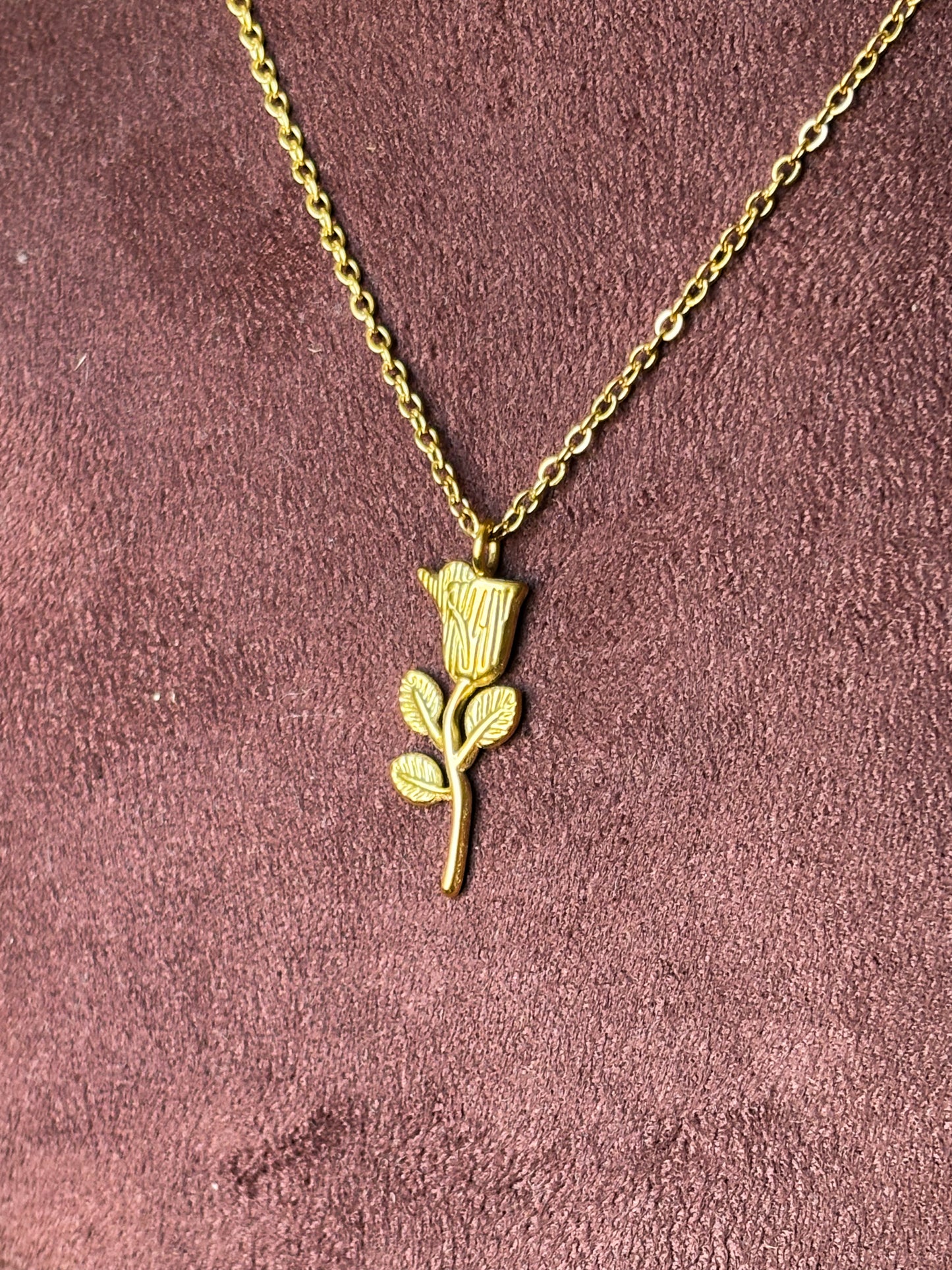 Gold necklace with a flower pendant.