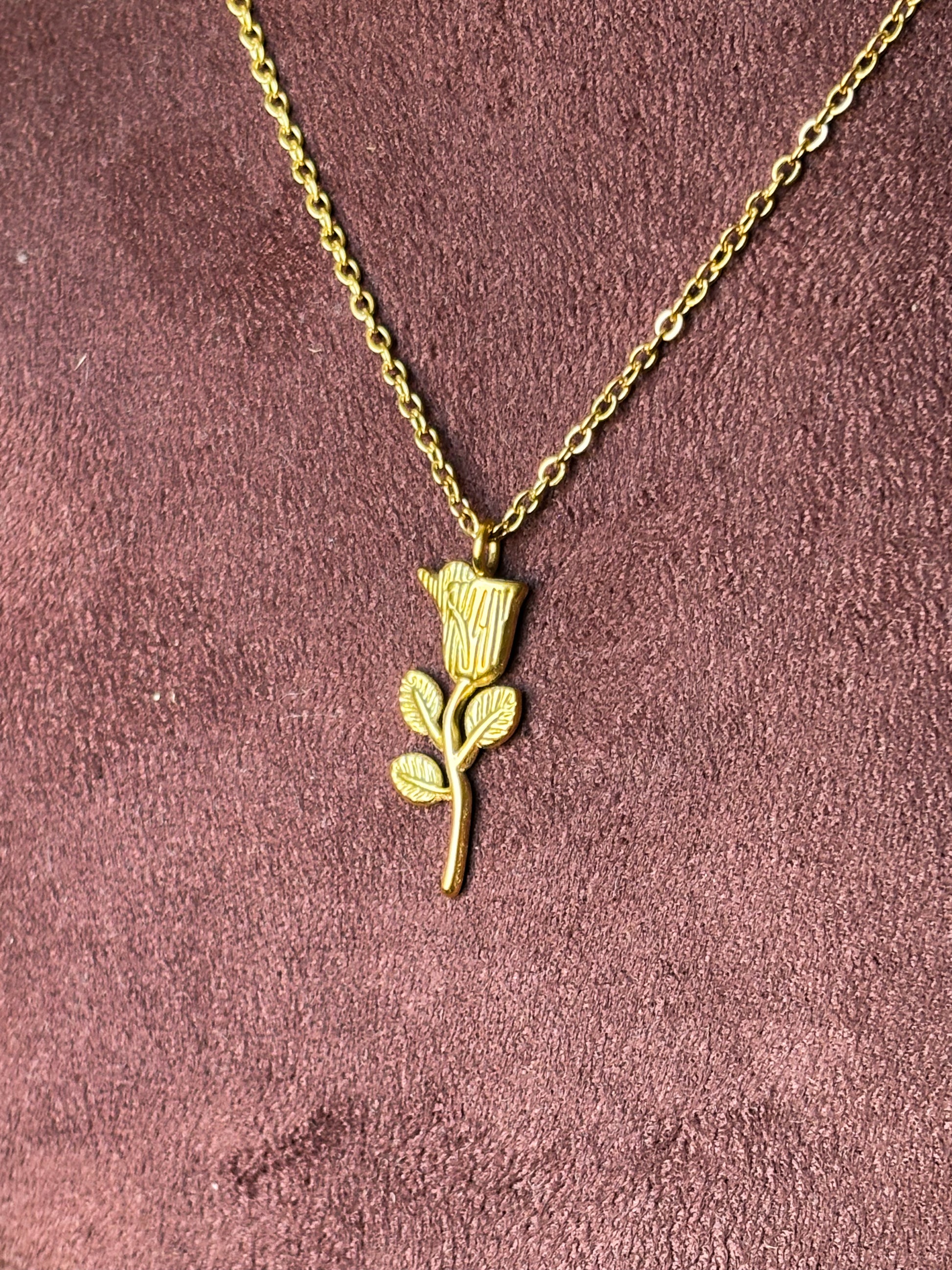 Gold necklace with a flower pendant.