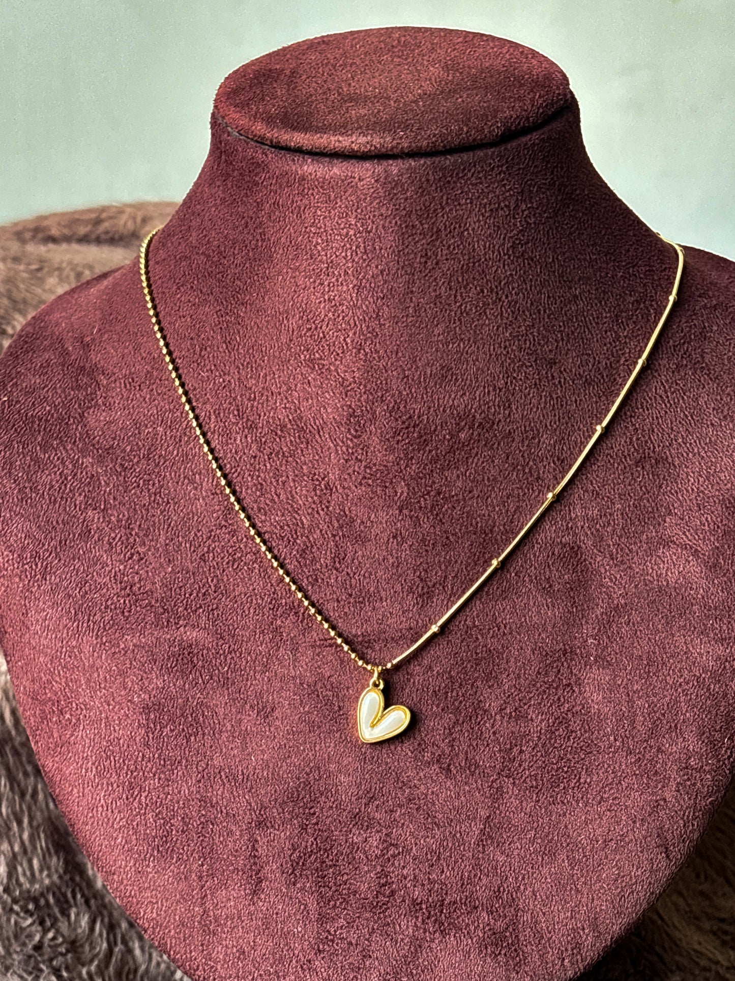 Gold-tone dual-chain necklace featuring a delicate ball chain and snake chain design with a white enamel heart pendant. Perfect minimalist jewellery for everyday wear.