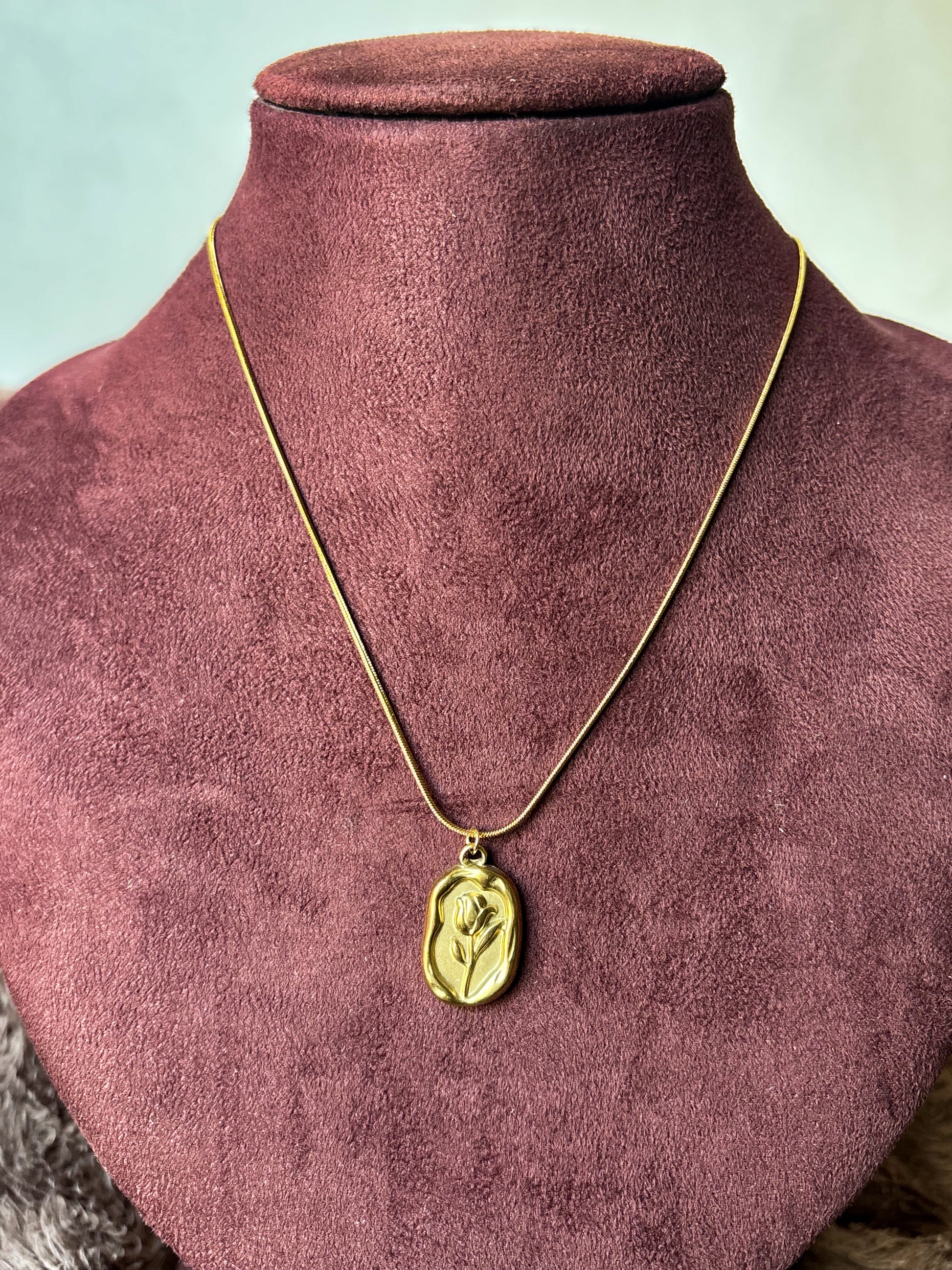 Elegant anti-tarnish gold-tone rose pendant necklace featuring a floral engraved rectangular charm on a sleek snake chain.Perfect for everyday wear, gifting, and minimalist jewellery styling.