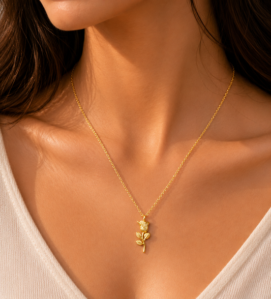 Gold necklace with a leaf pendant worn by a person