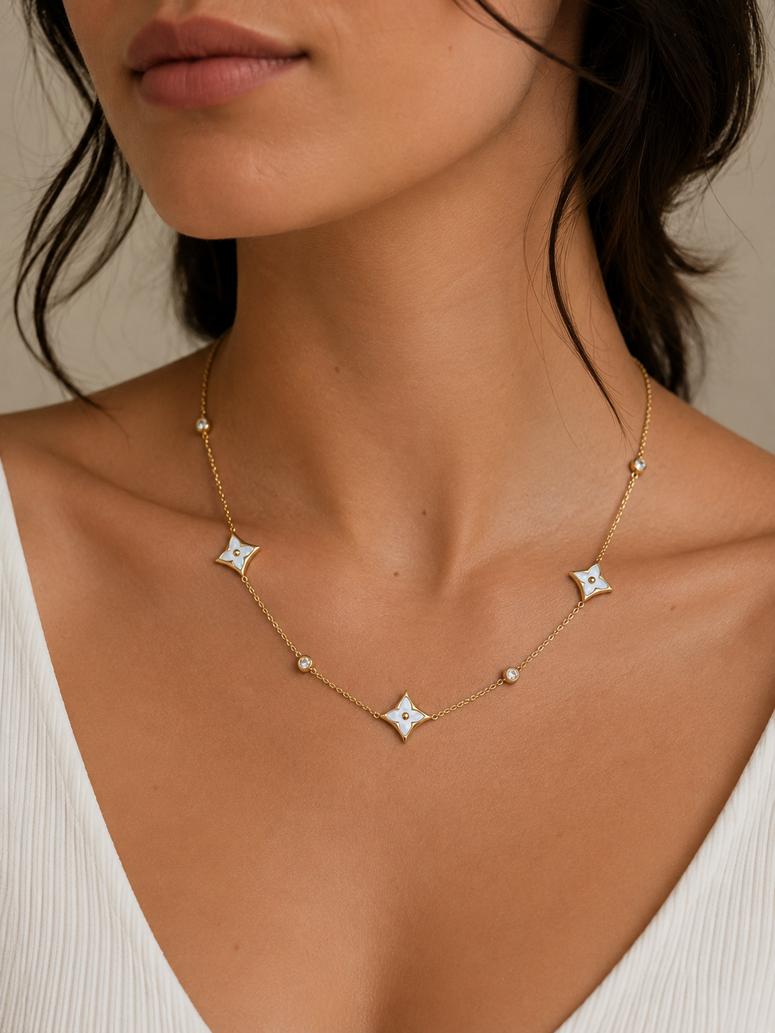 A delicate gold clover charm necklace with sparkling crystal accents, styled with a soft neutral outfit for an elegant everyday jewellery look.