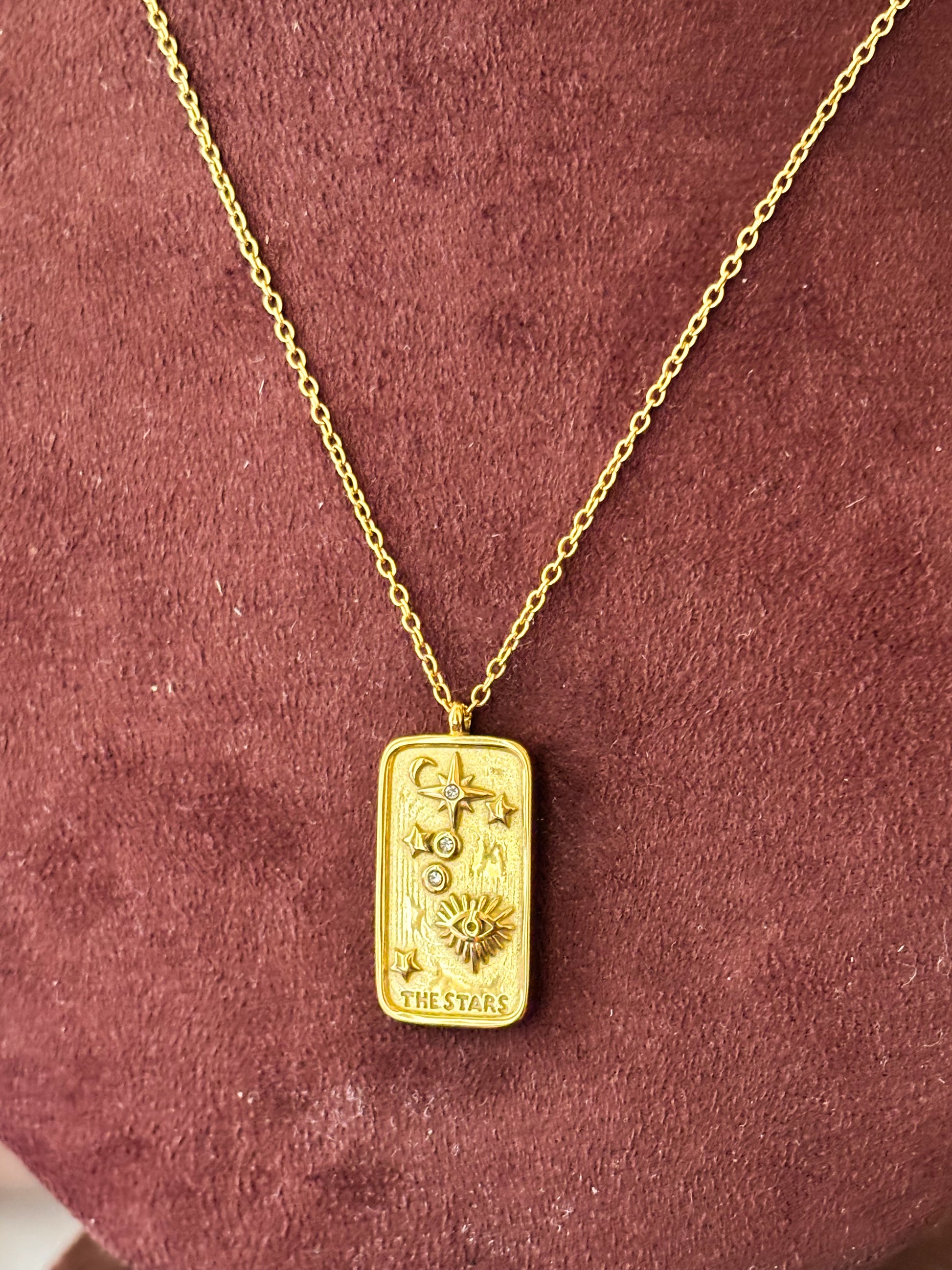 Elegant gold celestial tarot pendant necklace with sun, moon, and star detailing on a delicate chain, styled on a model’s neck for a minimal luxury look.