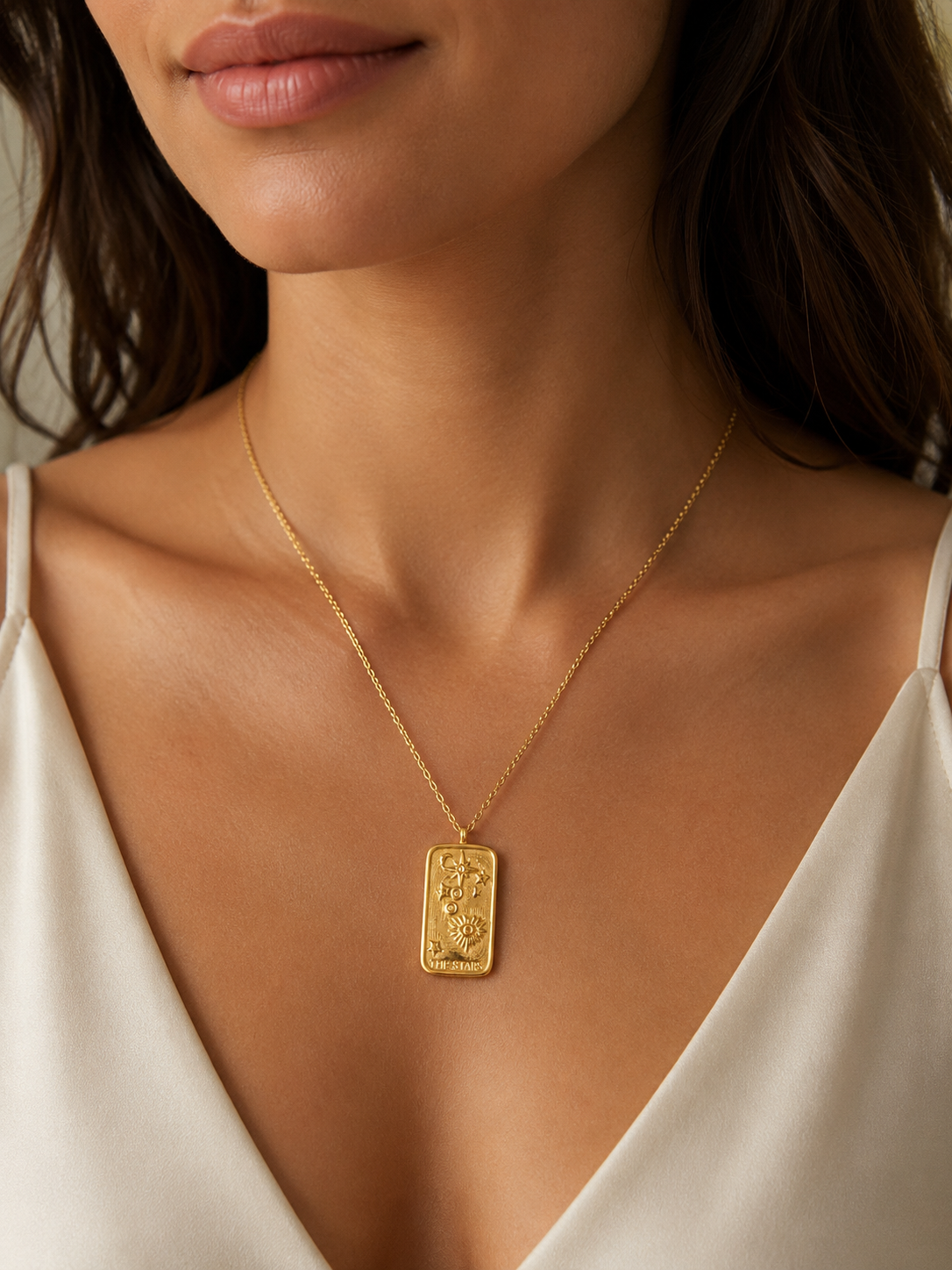 Elegant gold celestial tarot pendant necklace with sun, moon, and star detailing on a delicate chain, styled on a model’s neck for a minimal luxury look.